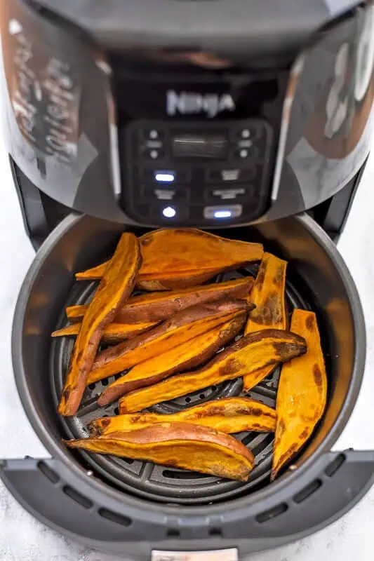 Sweet potato wedges in air fryer basket after cooking.