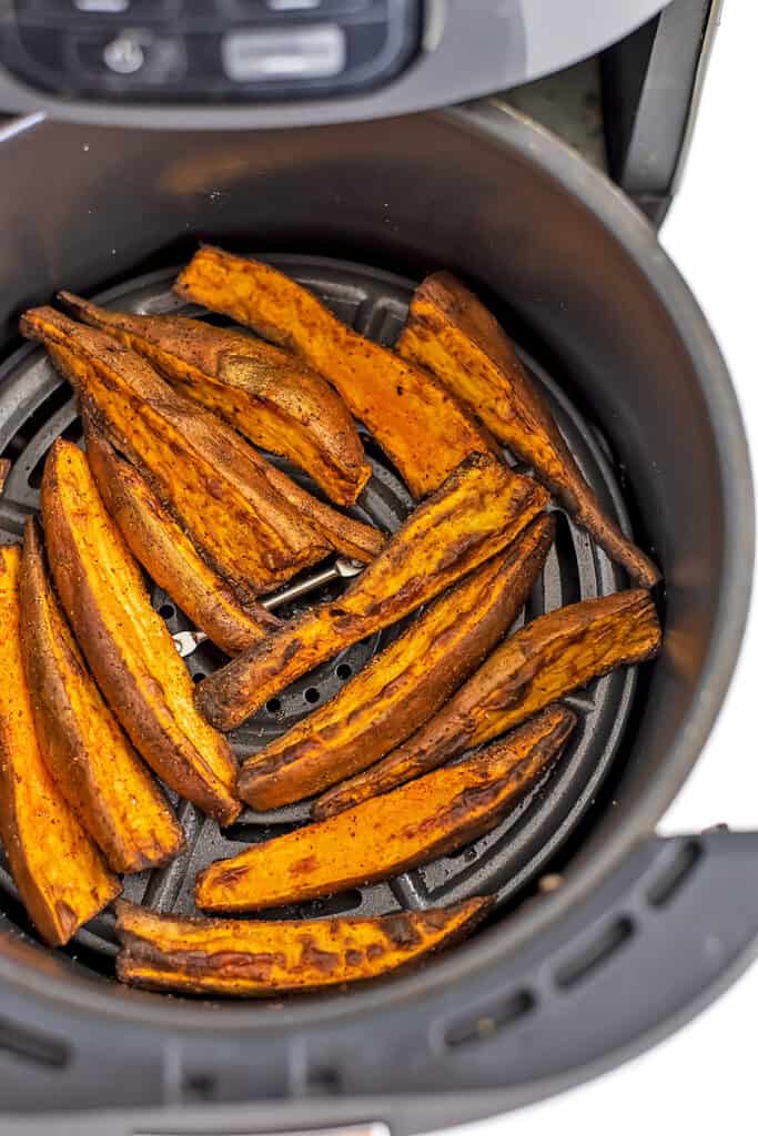 Air fryer basket filled with sweet potato wedges.