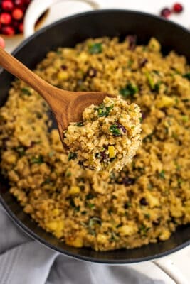 Large wooden spoon getting a spoonful of stuffing from skillet.