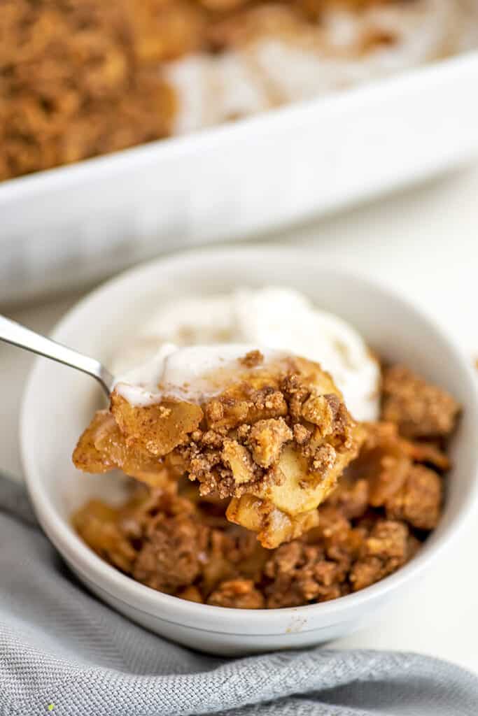 Spoon full of gluten free apple crumble with ice cream.