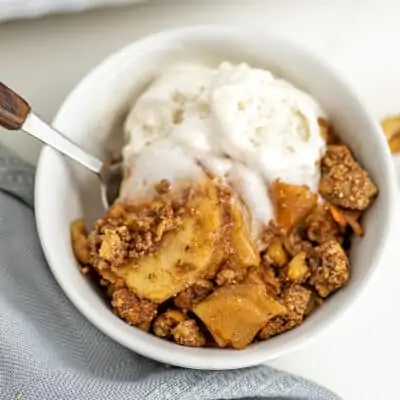 Bowl filled iwth gluten free apple crumble and ice cream.
