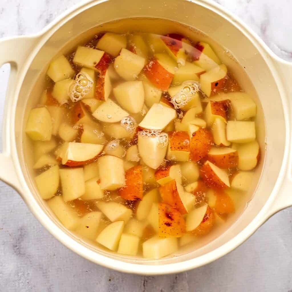 Cut potatoes with water in large pot.