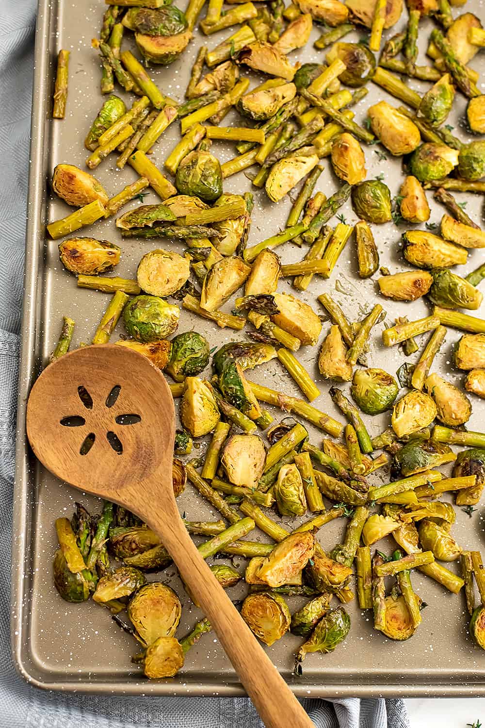 Wooden spoon on baking sheed with brussel sprouts and asparagus.