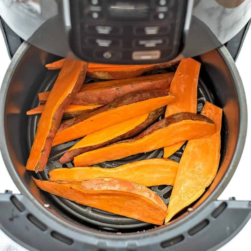 Sweet potato wedges in air fryer basket before cooking.