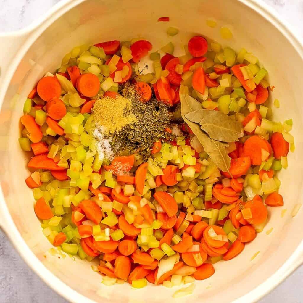 Spices, bay leaf and cooked veggies in a pot.