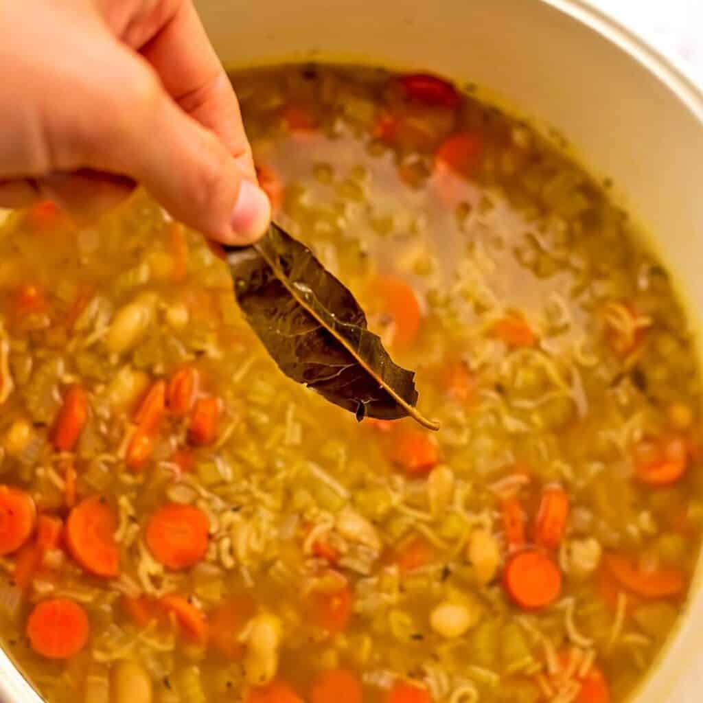 Bay leaf being removed from vegan rice soup.