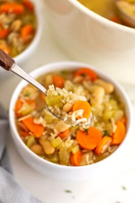 Spoonful of vegan rice soup in a white bowl.