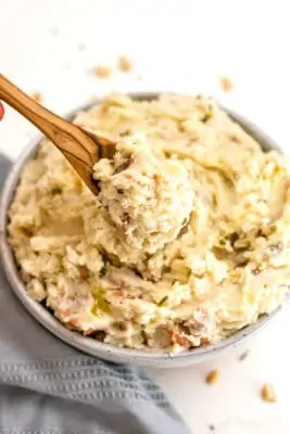 Spoon with Whole30 mashed potatoes on the spoon over a bowl of potatoes.