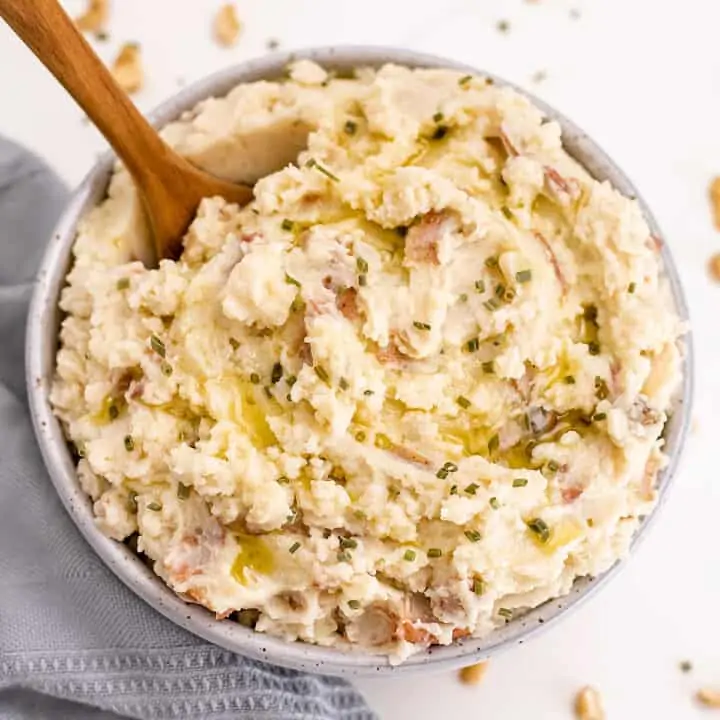 Dairy free mashed potatoes in a grey bowl with wooden spoon in potatoes.