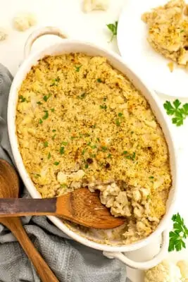 Vegan cauliflower casserole with a wooden spoon in the casserole dish.
