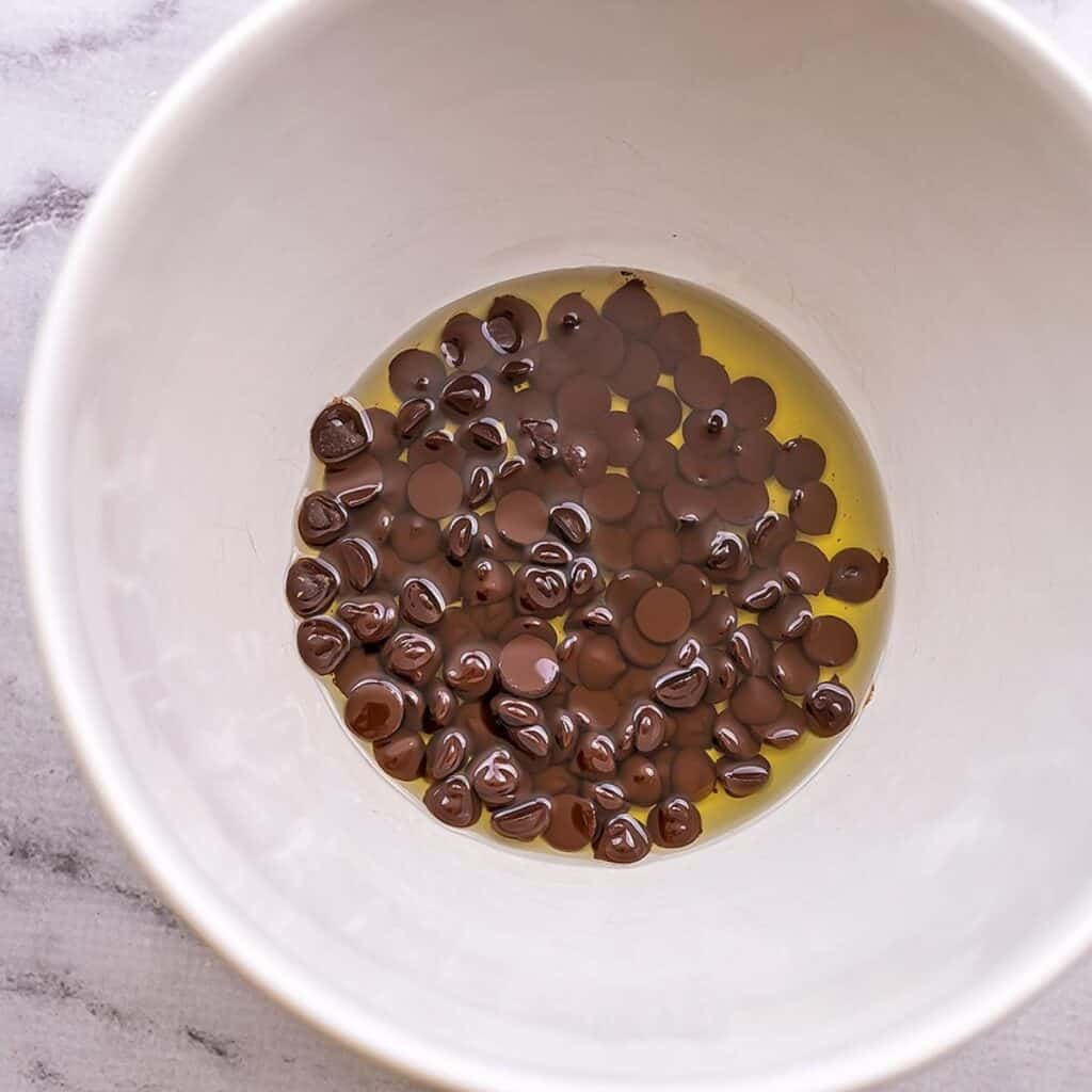 Chocolate chips with avocado oil in white bowl.