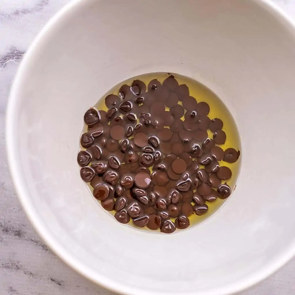 Chocolate chips with avocado oil in white bowl.