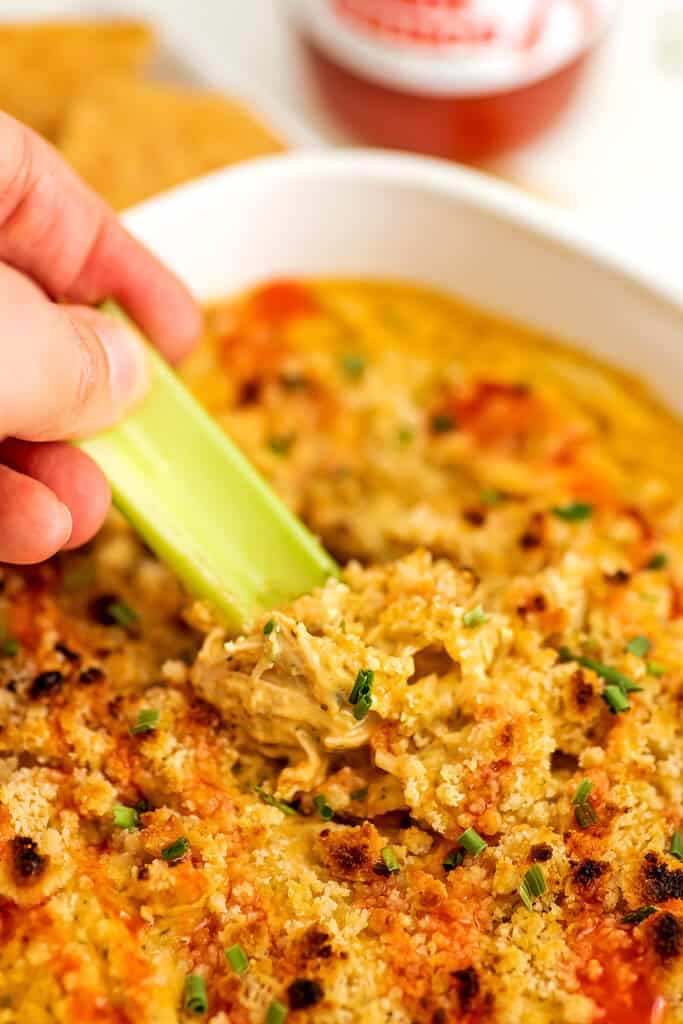 Celery stalk scooping out whole30 buffalo chicken dip.