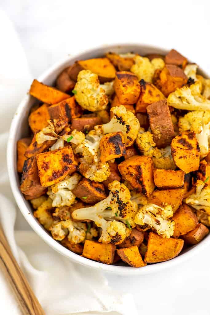 Bowl filled with roasted cauliflower and sweet potatoes.