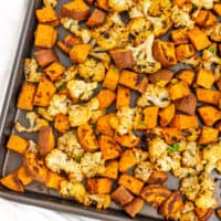 Sheet pan filled with roasted cauliflower and sweet potatoes.