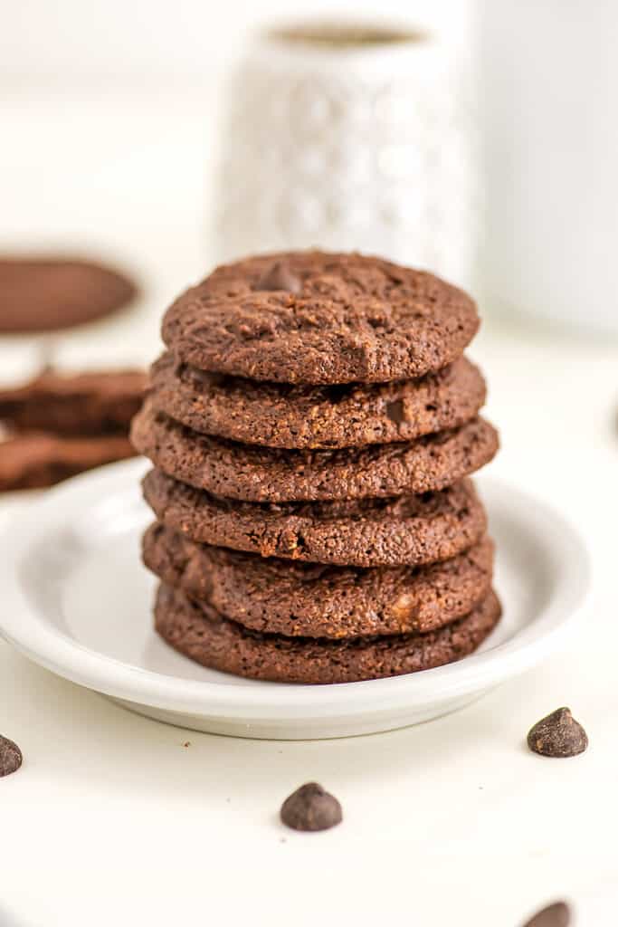 Large stack of double chocolate chip cookies on white plate. 
