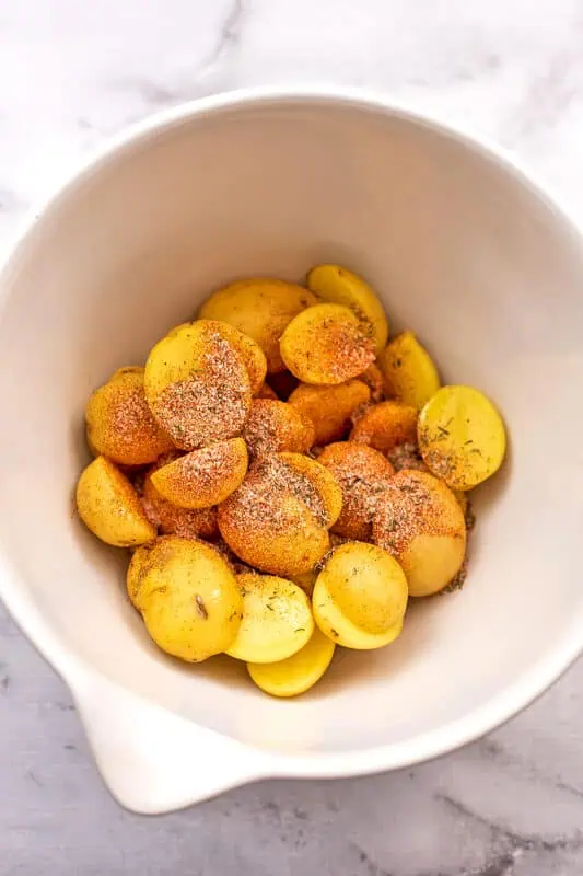 Baby potatoes in bowl with spices on top.