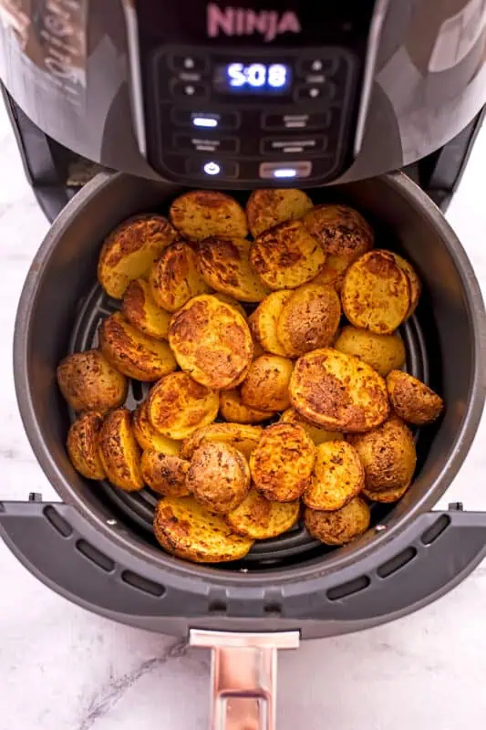 Mini potatoes in air fryer basket before shaking.