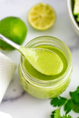 Spoon full of cilantro tahini dressing being held over the jar.