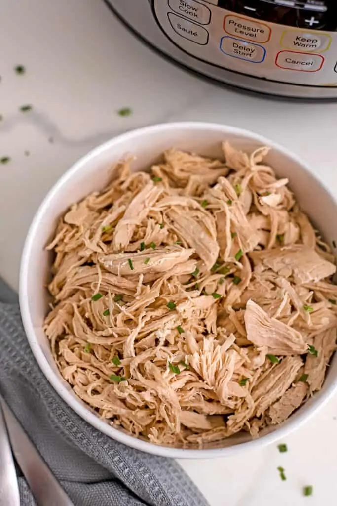 White bowl filled with pulled chicken cooked in the instant pot.