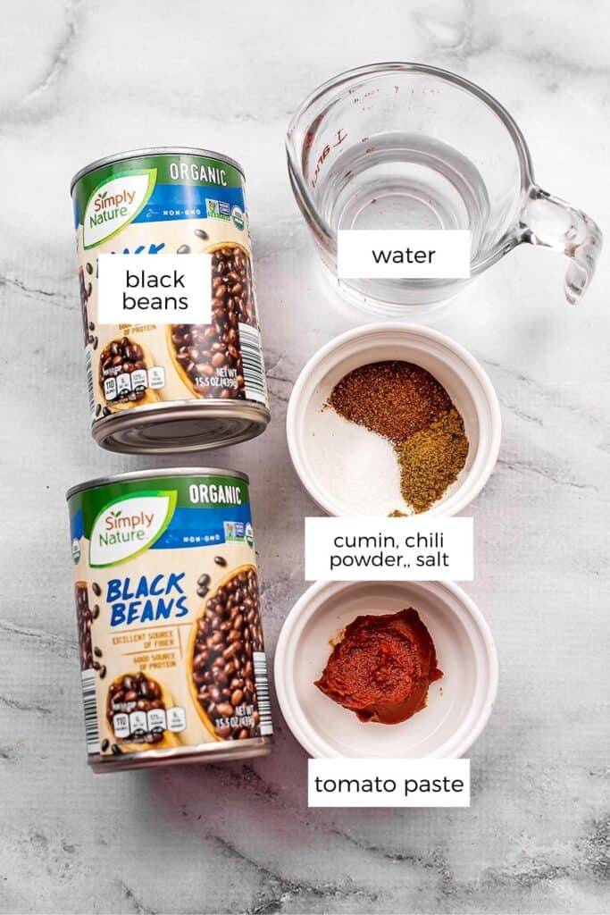 Ingredients for taco black beans on marble backdrop.