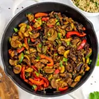 Cast iron skillet with white handle filled with Mexican sauteed vegetables.