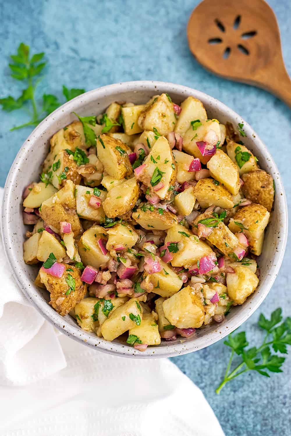 Parsley potato salad in a bowl with white napkin on the side.