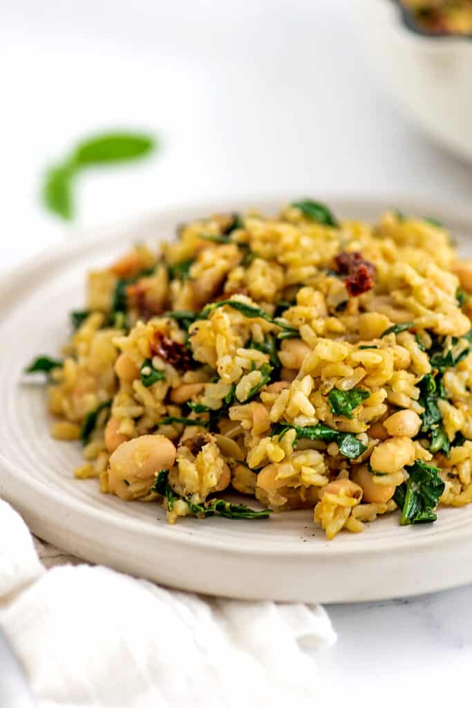 Tuscan white bean skillet on a large plate with a white napkin below the plate.