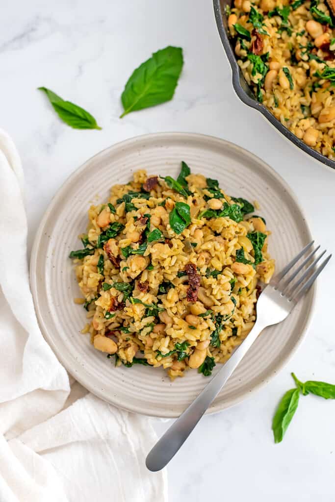Italian white beans and rice on a plate with a fork resting on the plate.