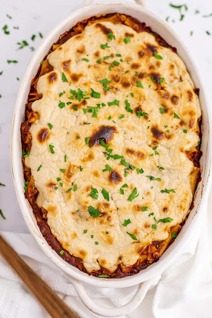 Casserole dish with vegan baked ziti, wooden spoon on side.