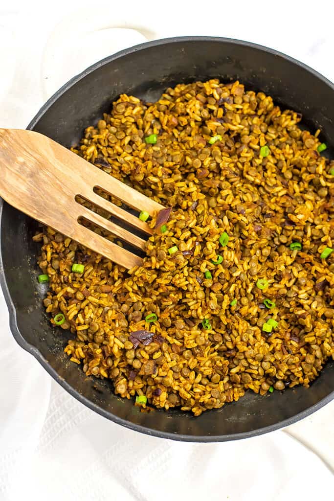 Lentil and rice vegan shawarma in cast iron skillet with wooden spatula.