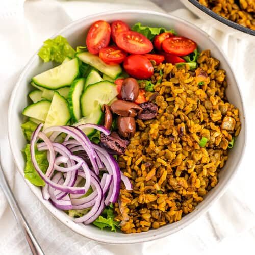 White bowl filled with vegan shawarma, onions, cucumber, tomato and lettuce.