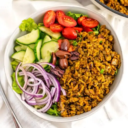 White bowl filled with vegan shawarma, onions, cucumber, tomato and lettuce.