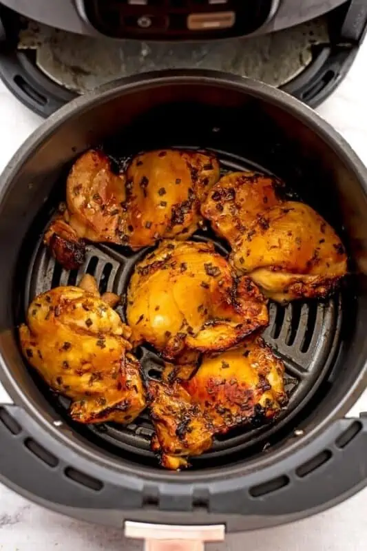 Air fryer basket filled with teriyaki chicken thighs after cooking.