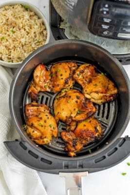 Grey air fryer basket filled with teriyaki chicken.