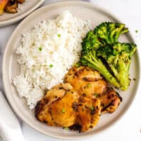 Teriyaki chicken thighs, broccoli and white rice on a plate.