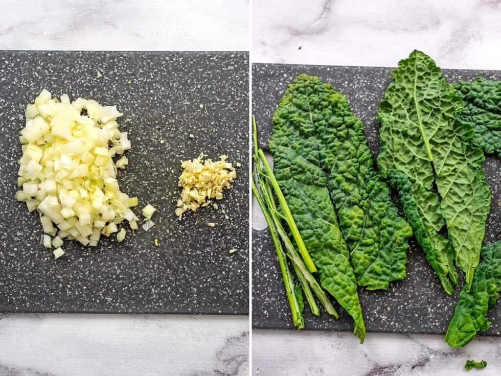 Chopped onions and garlic with destemmed kale on a grey cutting board.