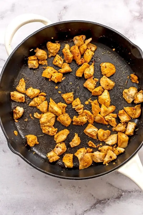Diced chicken in cast iron skillet after cooking.