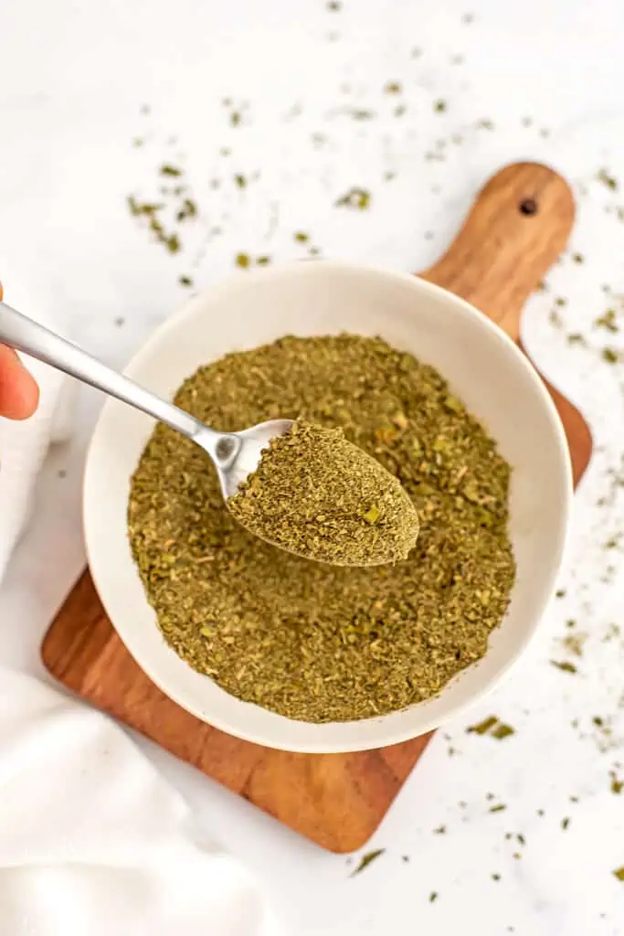 Wooden platter with bowl filled with italian seasoning.