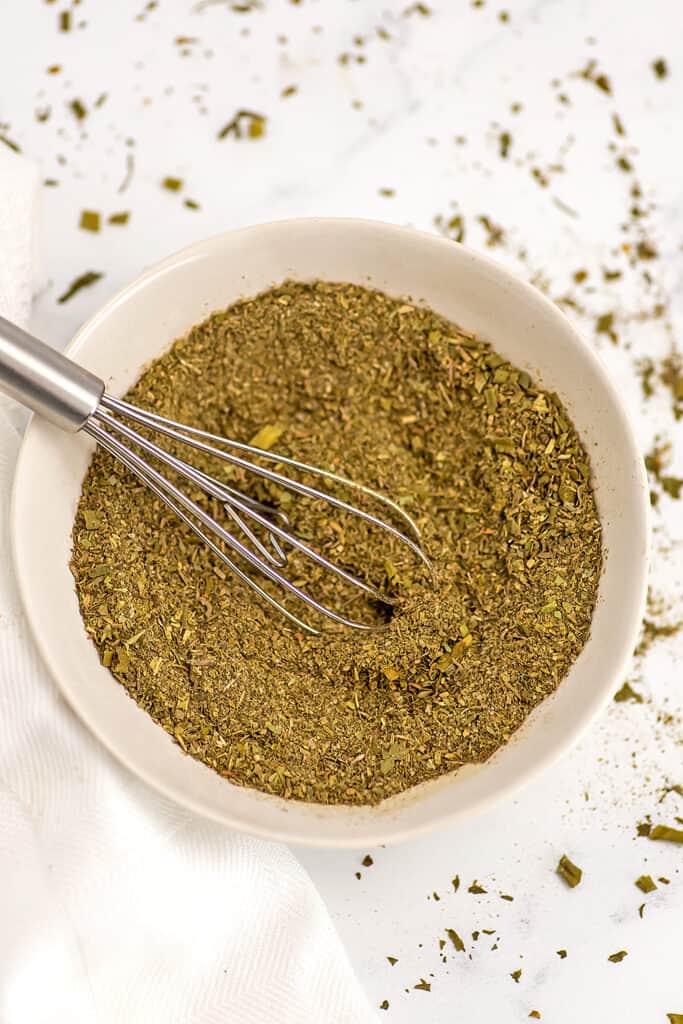 Whisk in a bowl filled with Italian seasoning substitute.