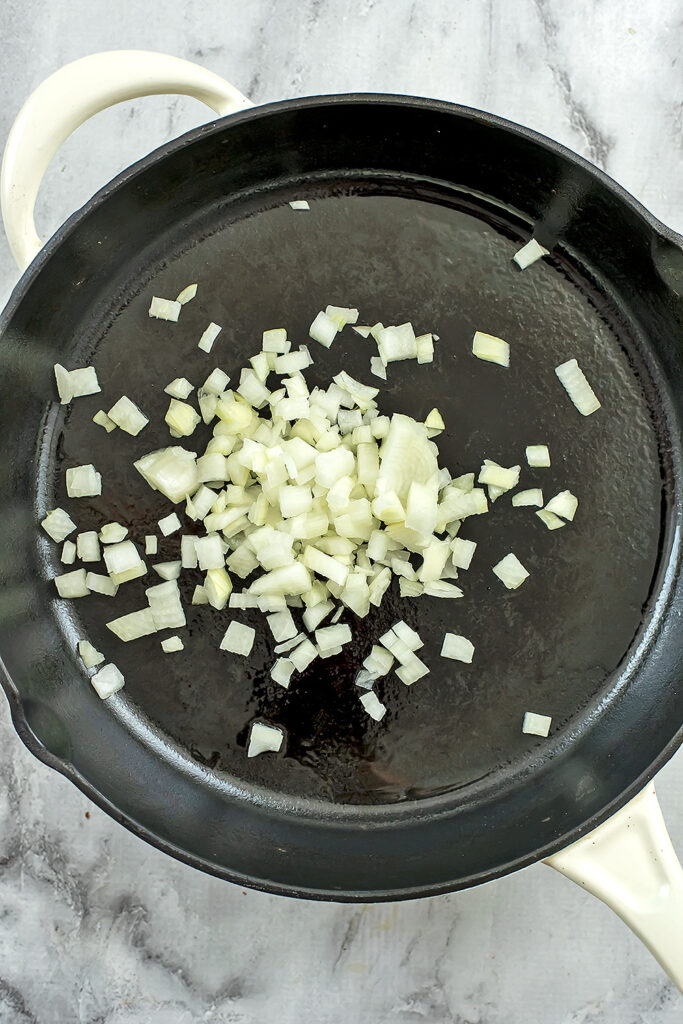 Diced onion in cast iron skillet before cooking. 