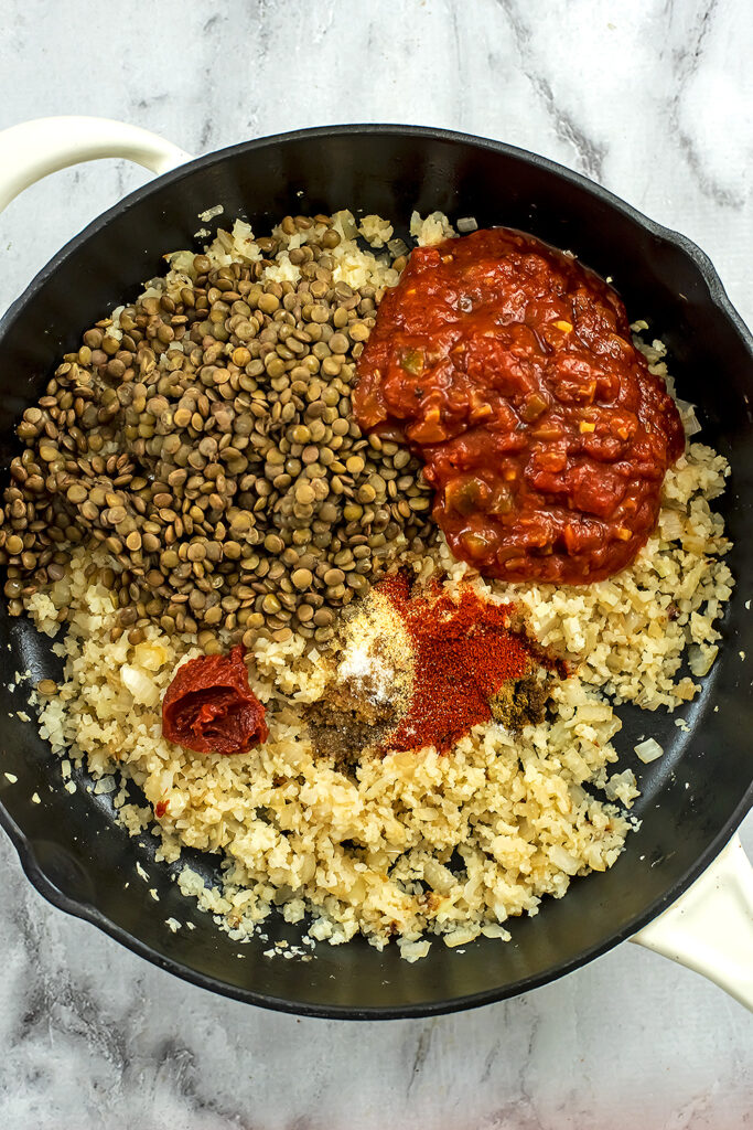 Cast iron skillet with cauliflower rice, lentils, salsa and spices. 
