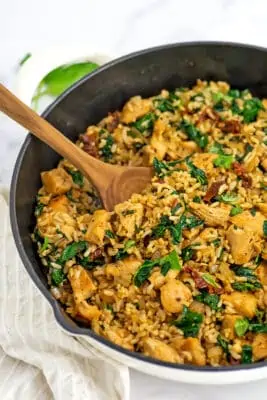 Cast iron skillet filled with italian chicken and rice with wooden spoon in skillet.