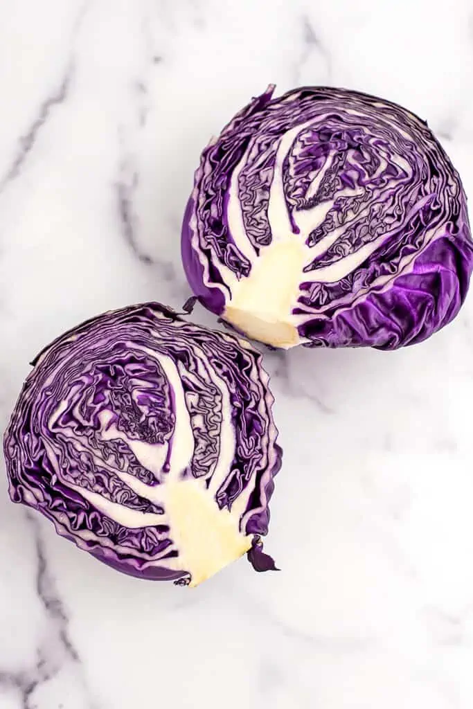 Red cabbage cut in half on marble counter.