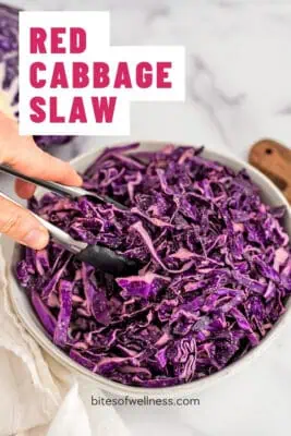 Tongs resting in a bowl of red cabbage slaw