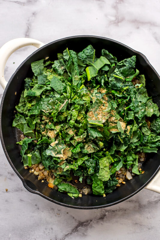 Chopped kale and spices added to skillet.