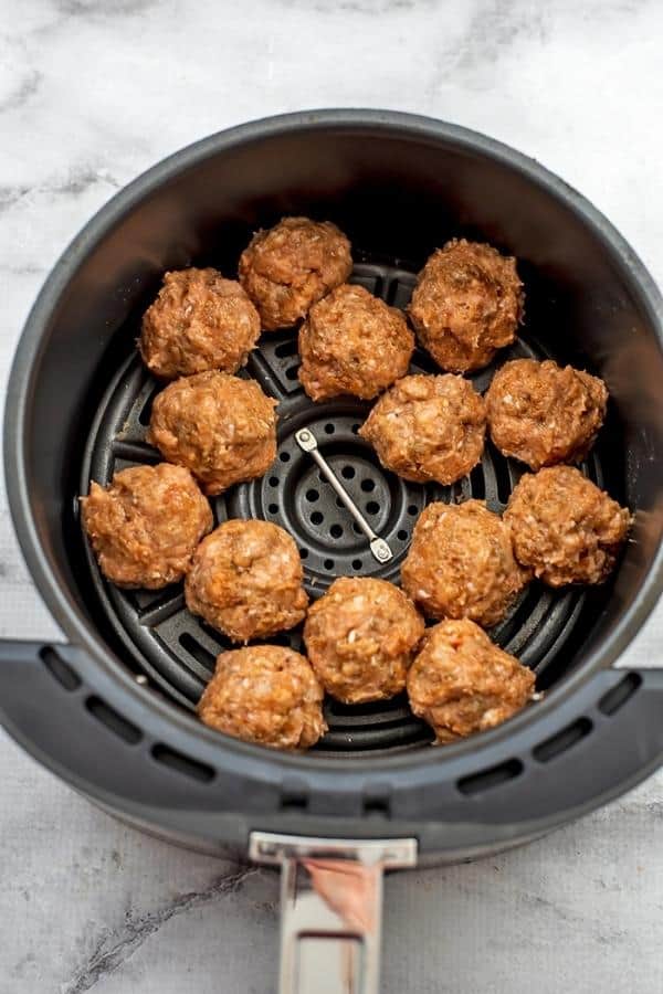 Raw chicken meatballs in the air fryer basket.
