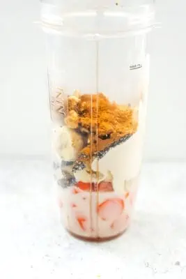The ingredients for a carrot banana smoothie in a blender cup.