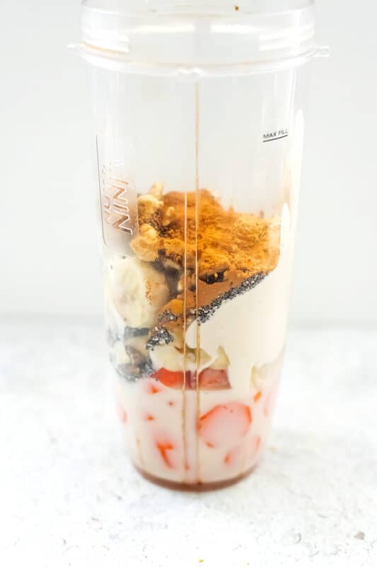 The ingredients for a carrot banana smoothie in a blender cup.