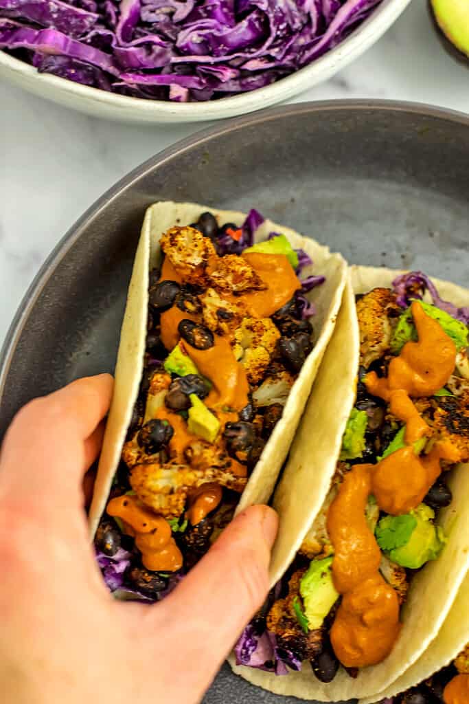 Hand holding cauliflower black bean taco.